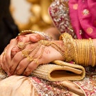 Muslim brides hands decorated with henna and gold jewellery.